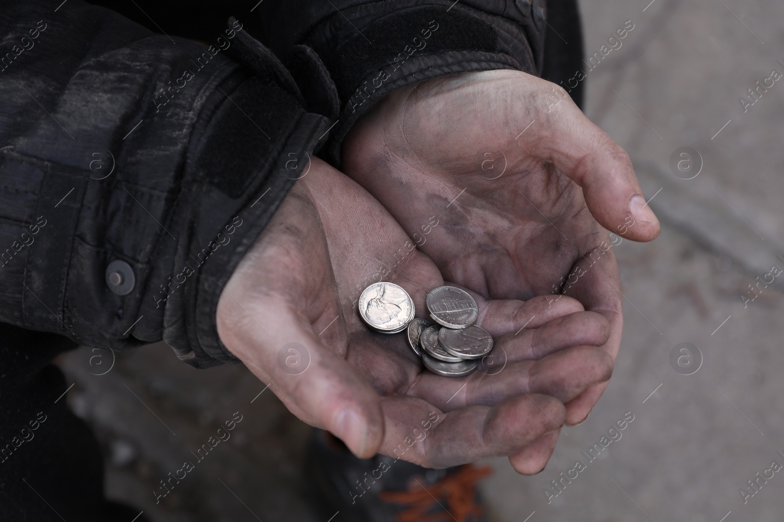 Photo of Poor homeless man holding coins outdoors, closeup