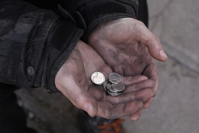 Photo of Poor homeless man holding coins outdoors, closeup