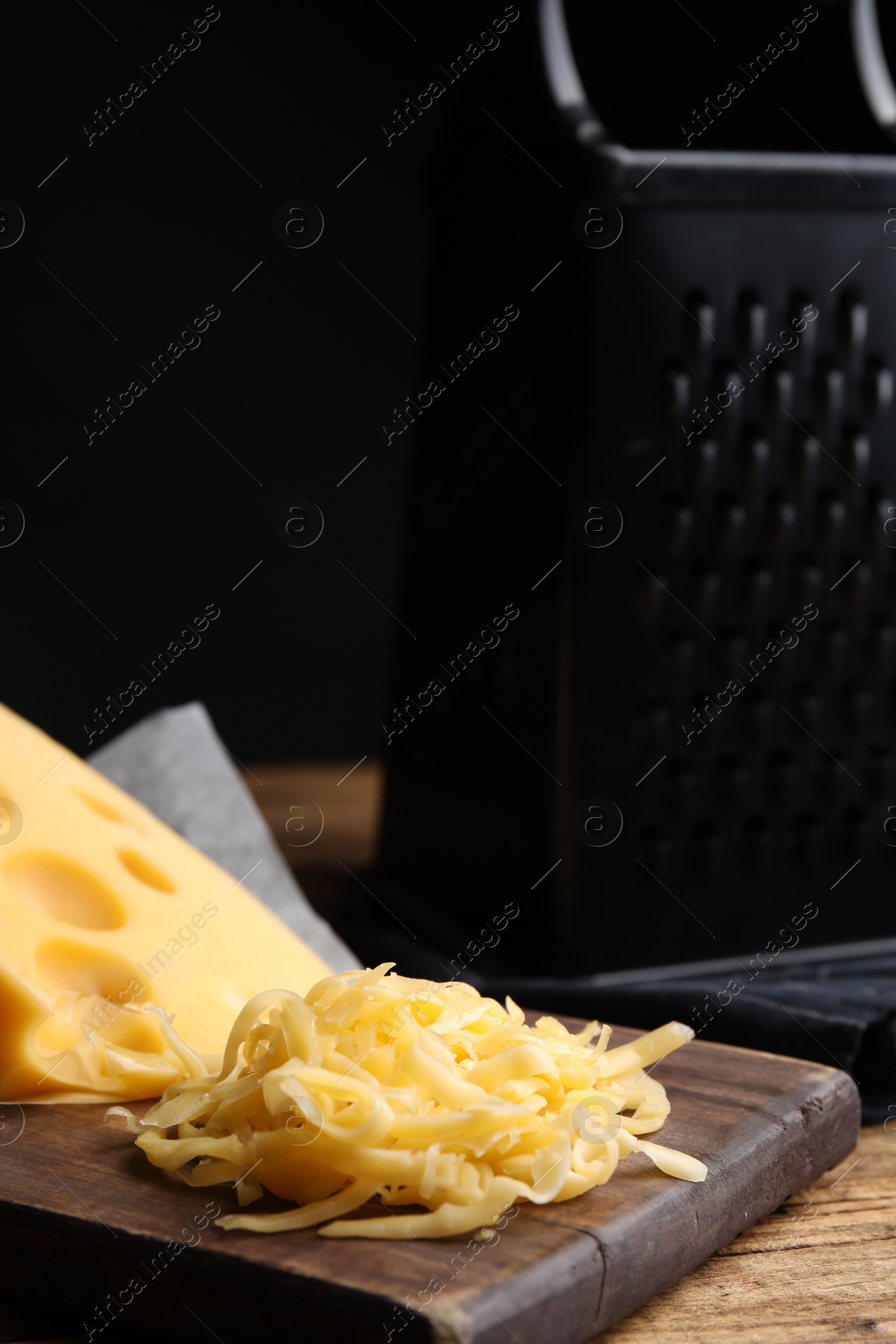 Photo of Pile of tasty grated cheese on wooden table
