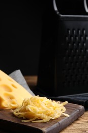 Photo of Pile of tasty grated cheese on wooden table