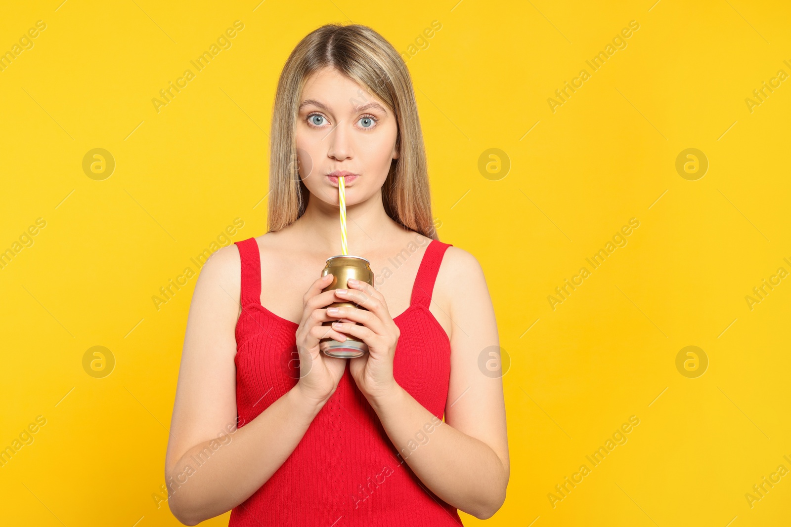 Photo of Beautiful woman drinking from beverage can on yellow background