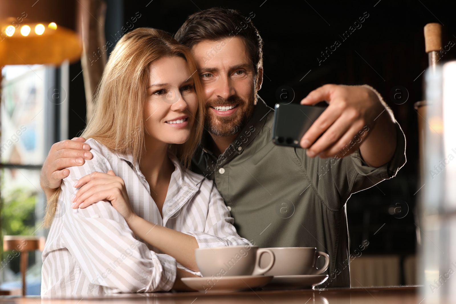 Photo of Romantic date. Happy couple taking selfie in cafe