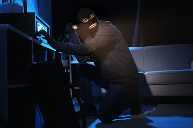 Photo of Thief with flashlight near steel safe indoors at night