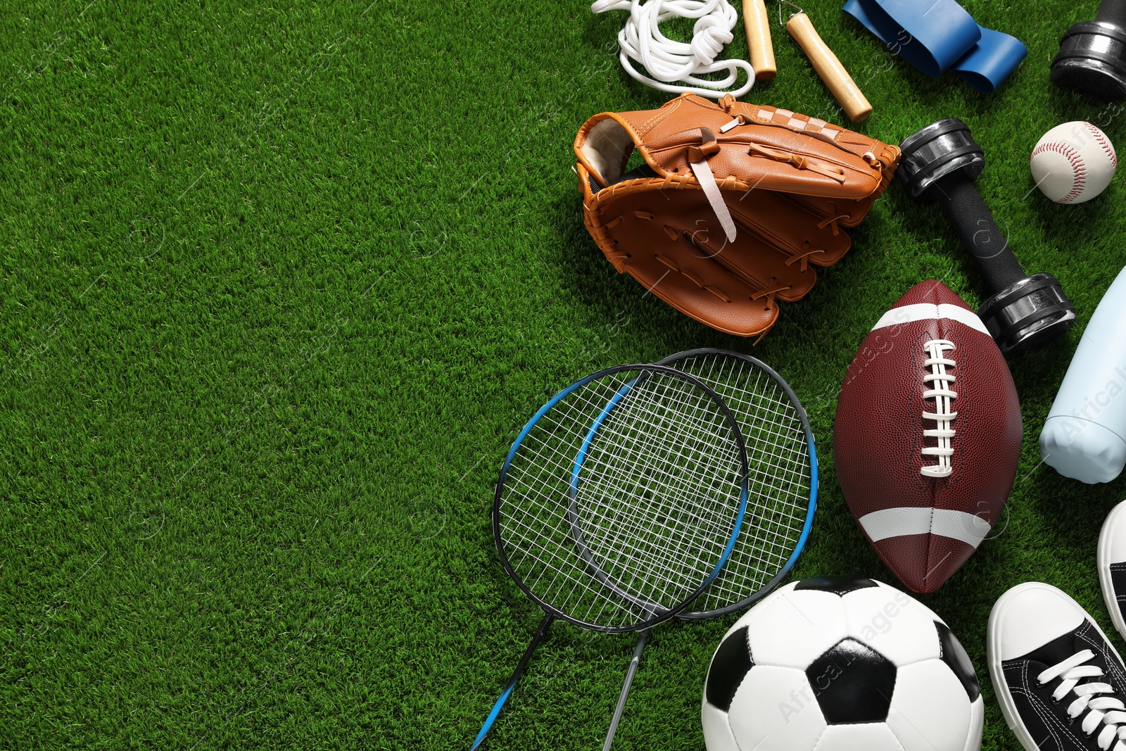 Photo of Different sports equipment on green grass, flat lay. Space for text