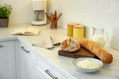 Photo of Fresh bread and dairy products on countertop in modern kitchen. Space for text