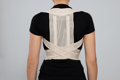 Photo of Closeup of woman with orthopedic corset on grey background, back view