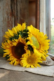 Photo of Beautiful sunflowers on cloth near window indoors