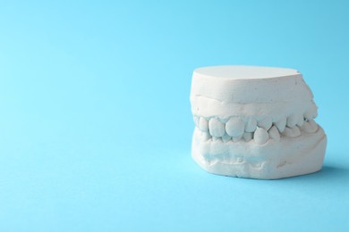 Photo of Dental model with gums on light blue background, space for text. Cast of teeth