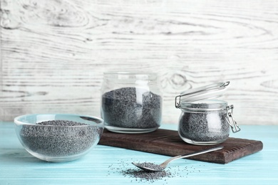Photo of Poppy seeds in different dishware on wooden table