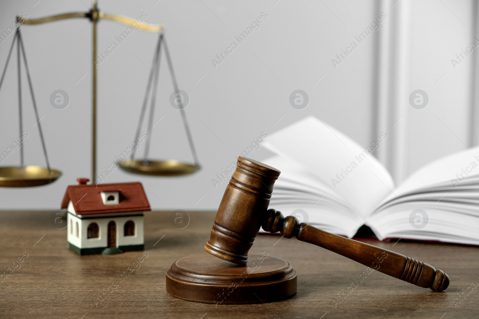 Photo of Construction and land law concepts. Judge gavel, scales of justice, open book with house model on wooden table