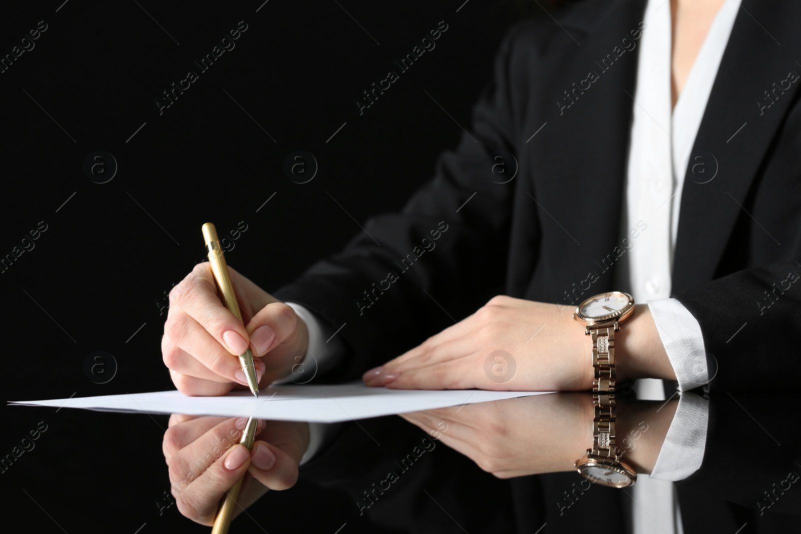 Photo of Woman writing on sheet of paper at glass table, closeup