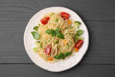 Photo of Delicious pasta primavera with tomatoes, basil and broccoli on grey table, top view