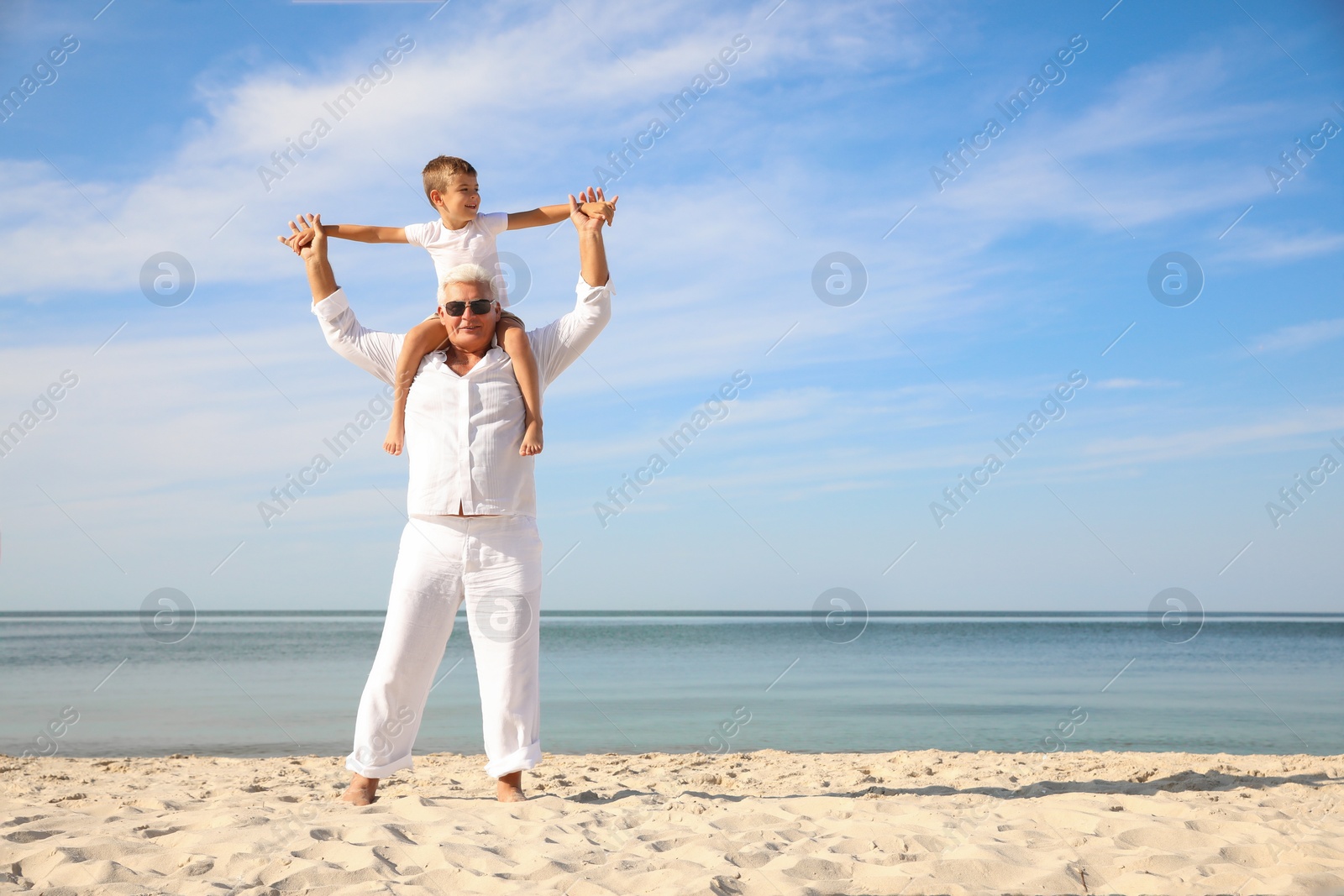 Photo of Cute little boy with grandfather spending time together on sea beach