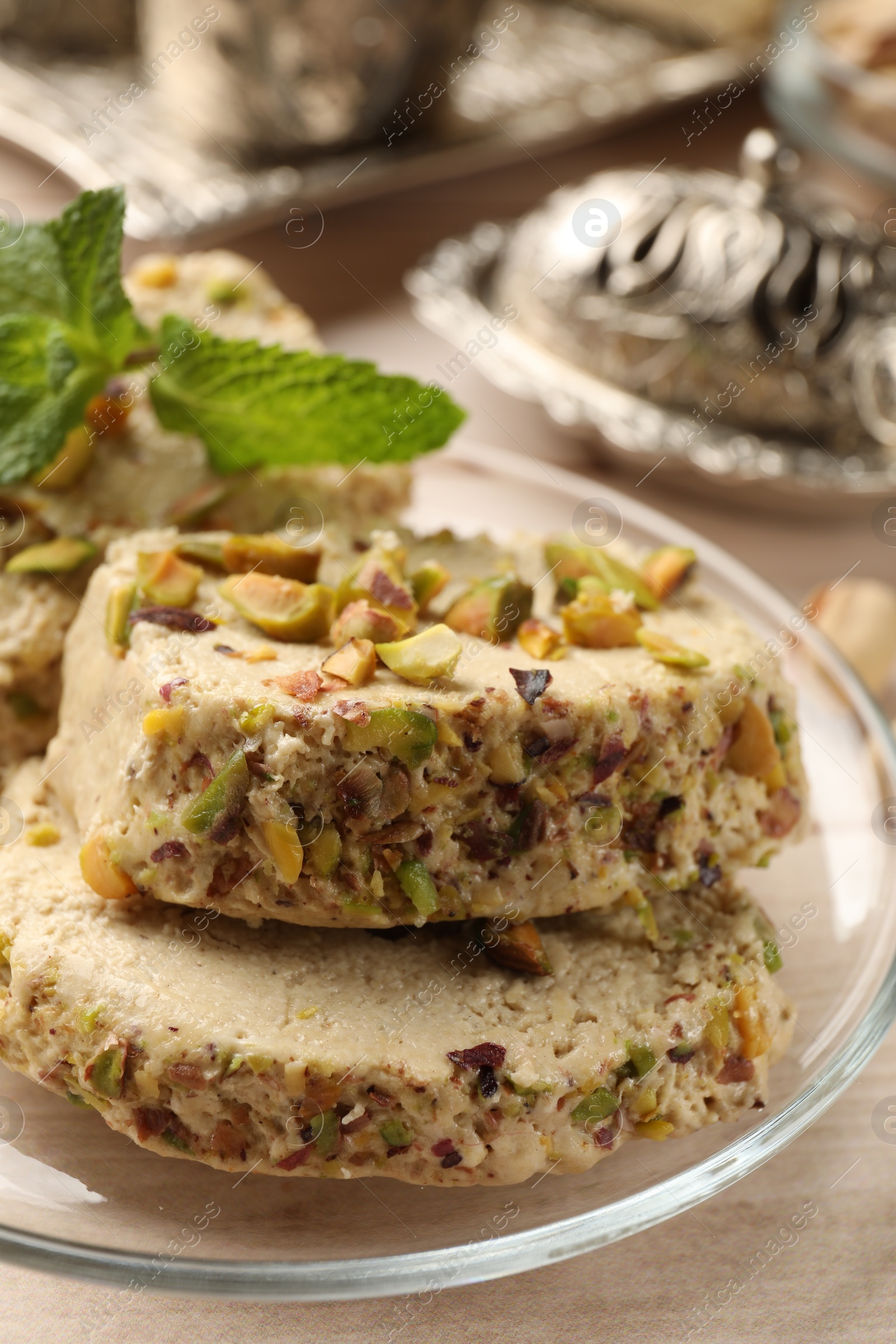 Photo of Tasty halva with pistachios and mint on table, closeup