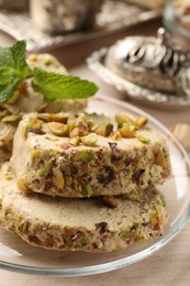 Photo of Tasty halva with pistachios and mint on table, closeup
