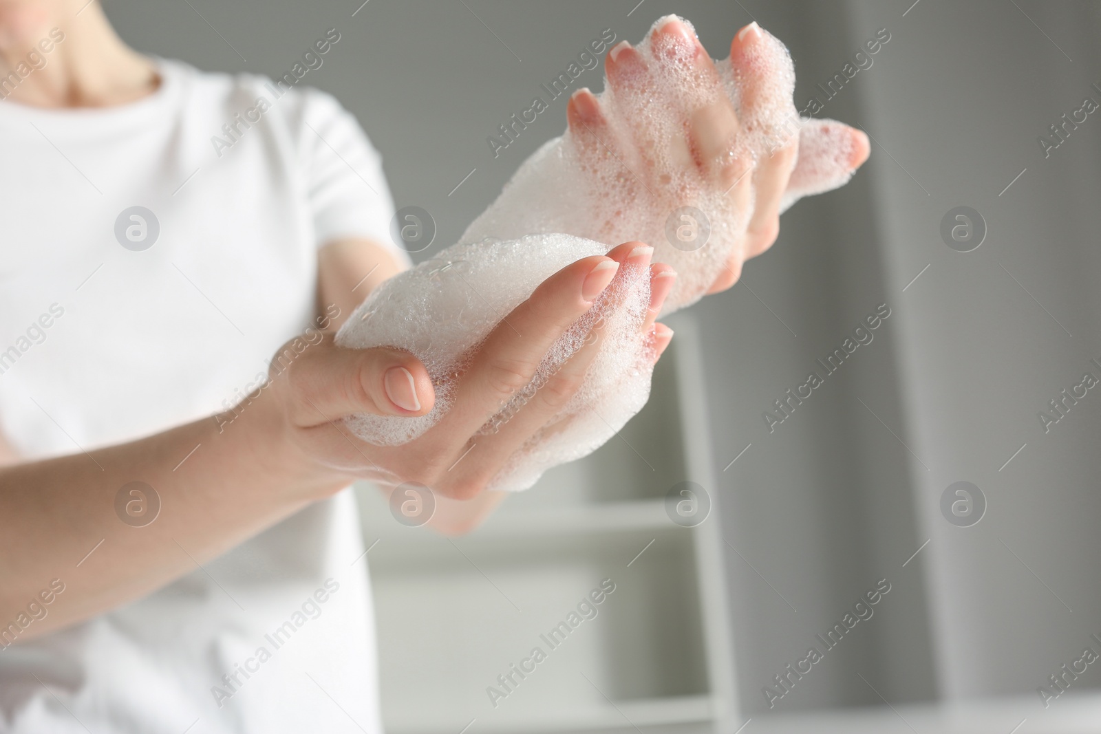 Photo of Woman washing hands with cleansing foam near sink in bathroom, closeup