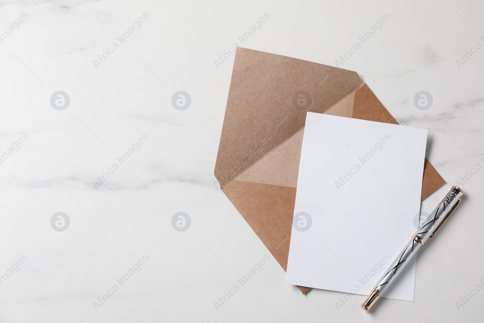 Photo of Blank sheet of paper, pen and letter envelope on white marble table, top view. Space for text