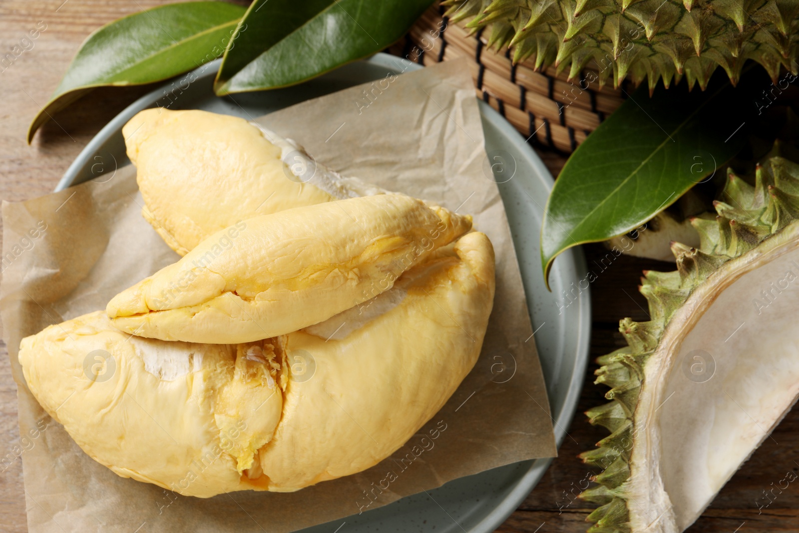 Photo of Fresh ripe durian and leaves on wooden table, flat lay