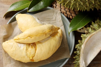 Fresh ripe durian and leaves on wooden table, flat lay