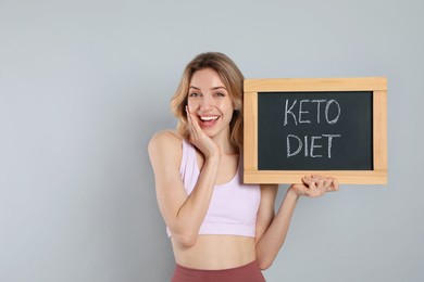 Photo of Woman holding blackboard with phrase Keto Diet on grey background