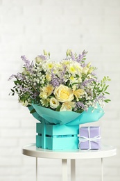 Photo of Beautiful bouquet of flowers and gift box on table against light background