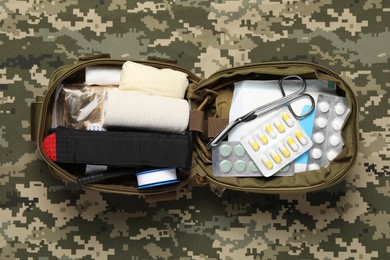 Photo of Military first aid kit on camouflage fabric, top view