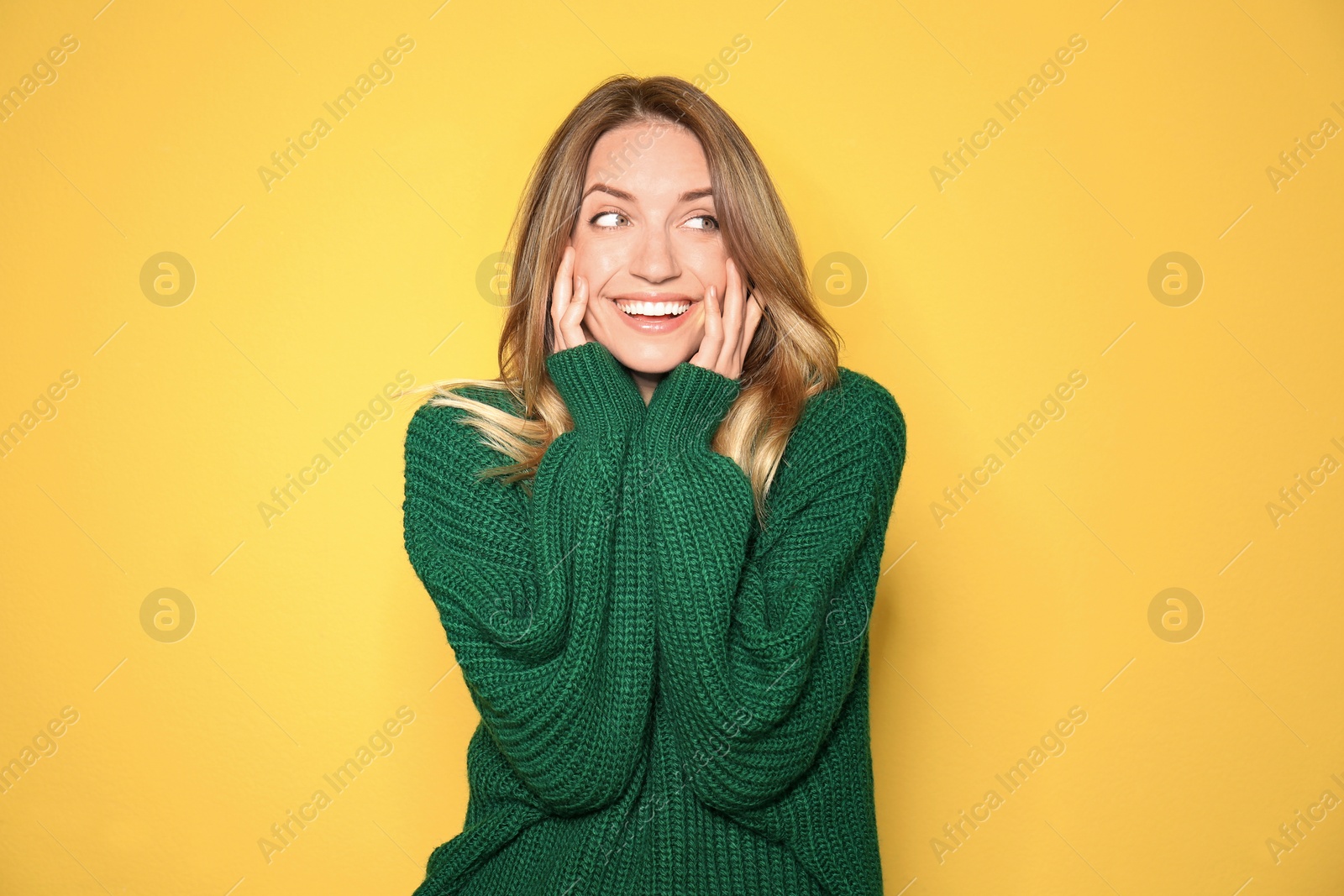 Image of Happy young woman wearing warm sweater on yellow background