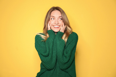 Image of Happy young woman wearing warm sweater on yellow background