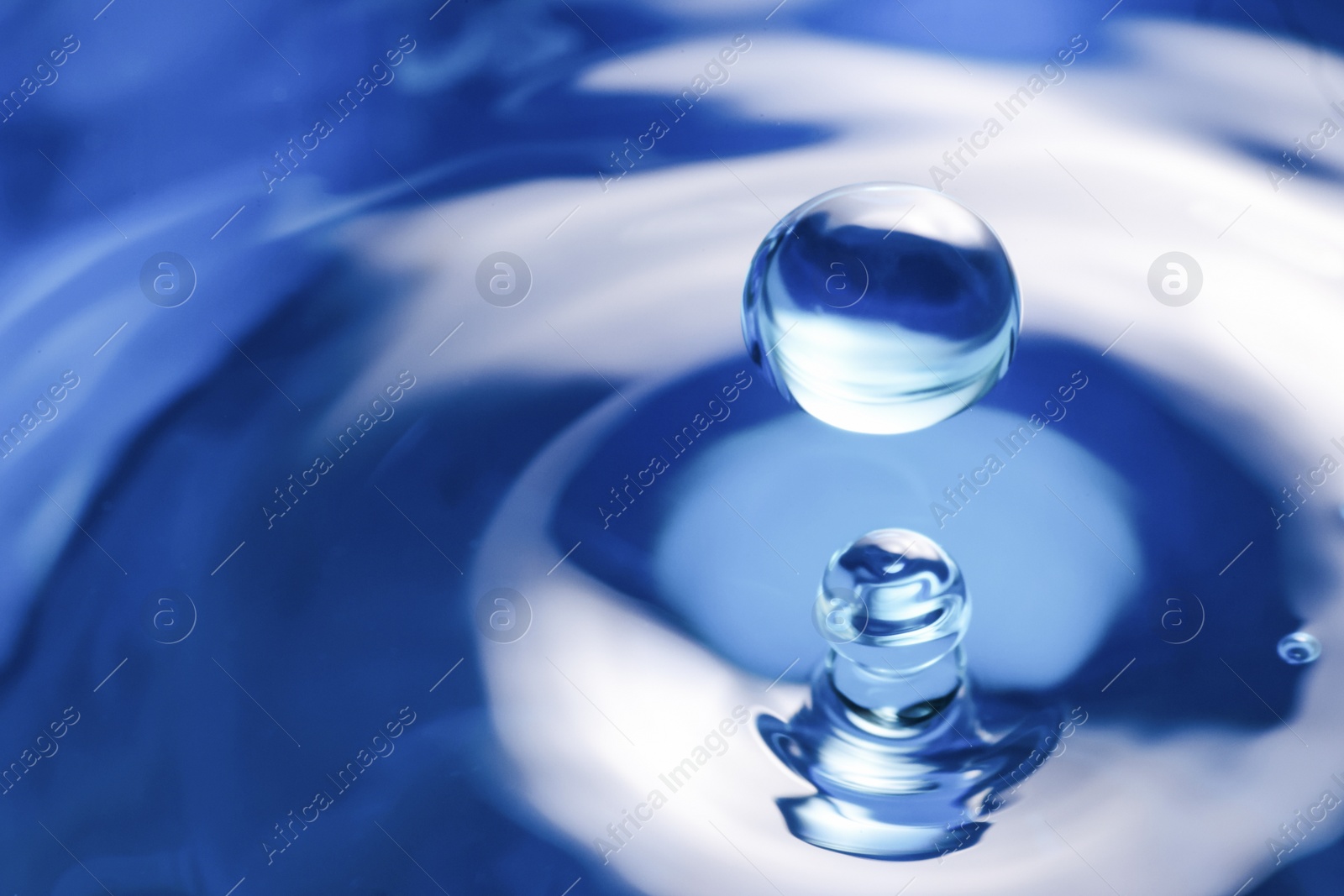 Photo of Splash of clear water with drops on blue background, closeup