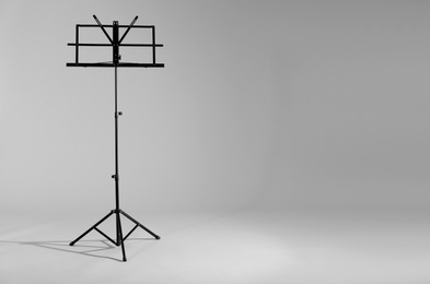 Photo of Empty music note stand on grey background. Space for text