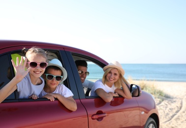 Photo of Happy family in car at beach on sunny day
