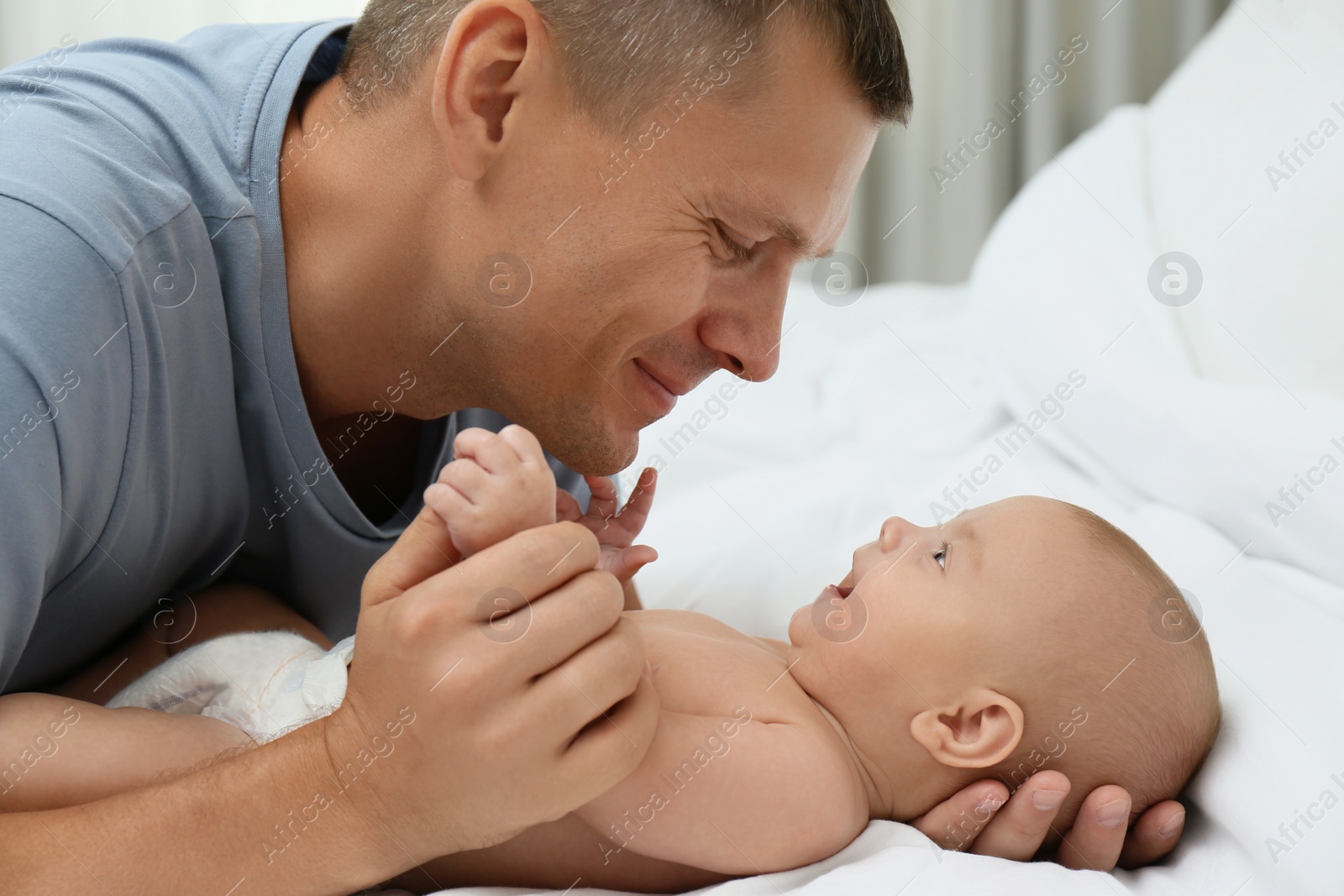 Photo of Happy father with his cute baby on bed