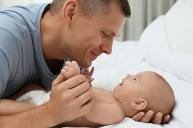 Photo of Happy father with his cute baby on bed