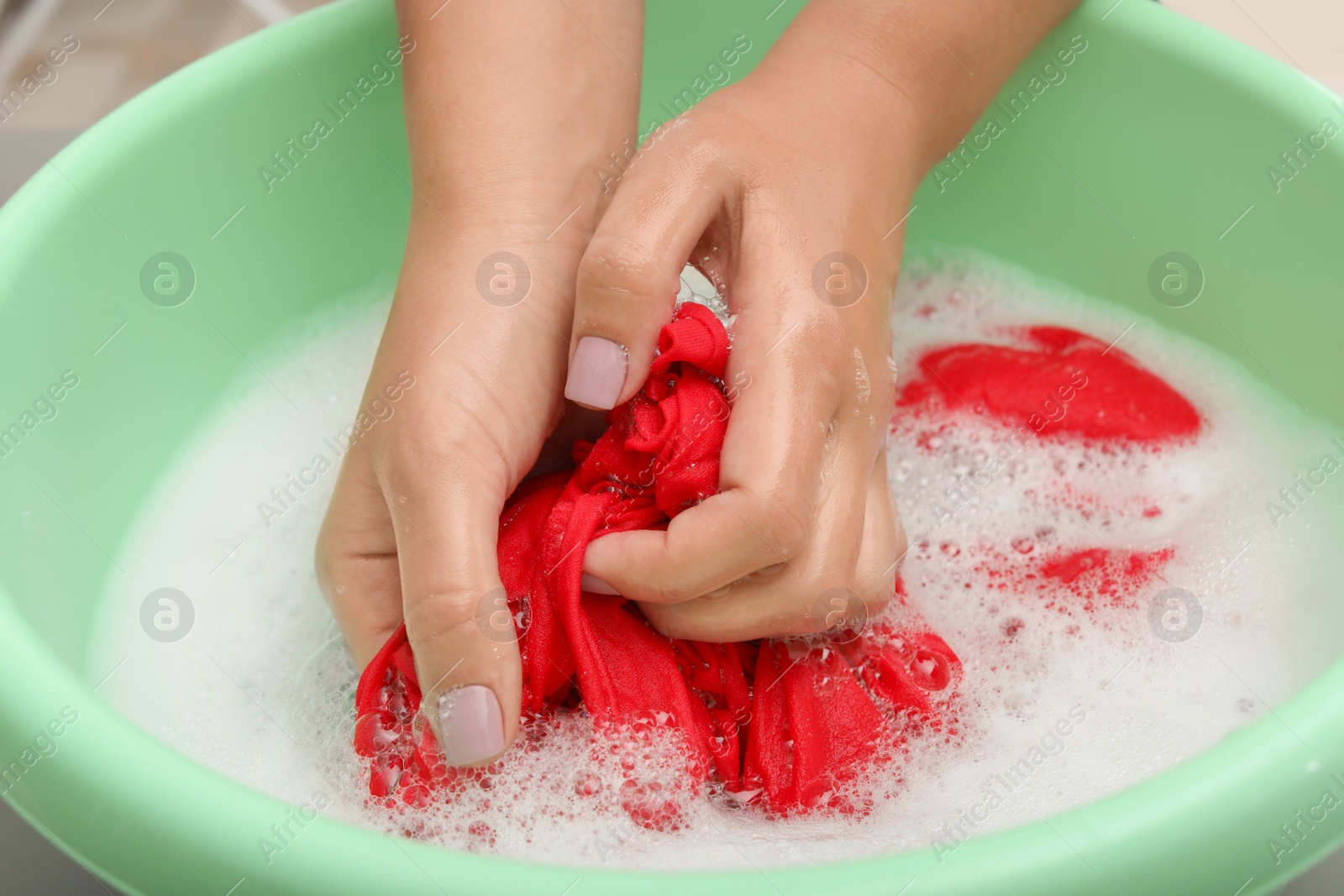 Photo of Woman washing color clothes in basin, closeup