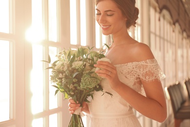 Photo of Bride in beautiful wedding dress with bouquet in restaurant, closeup