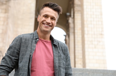 Photo of Portrait of handsome young man on city street. Space for text