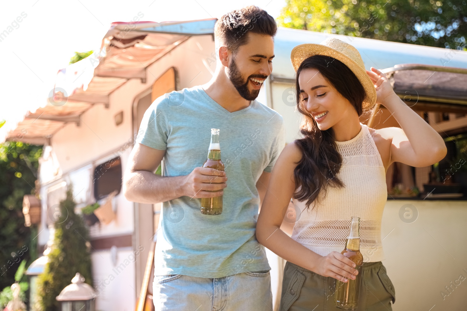 Photo of Happy couple with bottles of beer near motorhome. Camping season