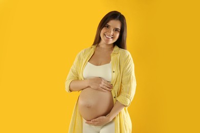 Photo of Happy young pregnant woman on yellow background