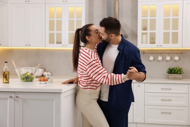 Photo of Lovely young couple kissing together in kitchen