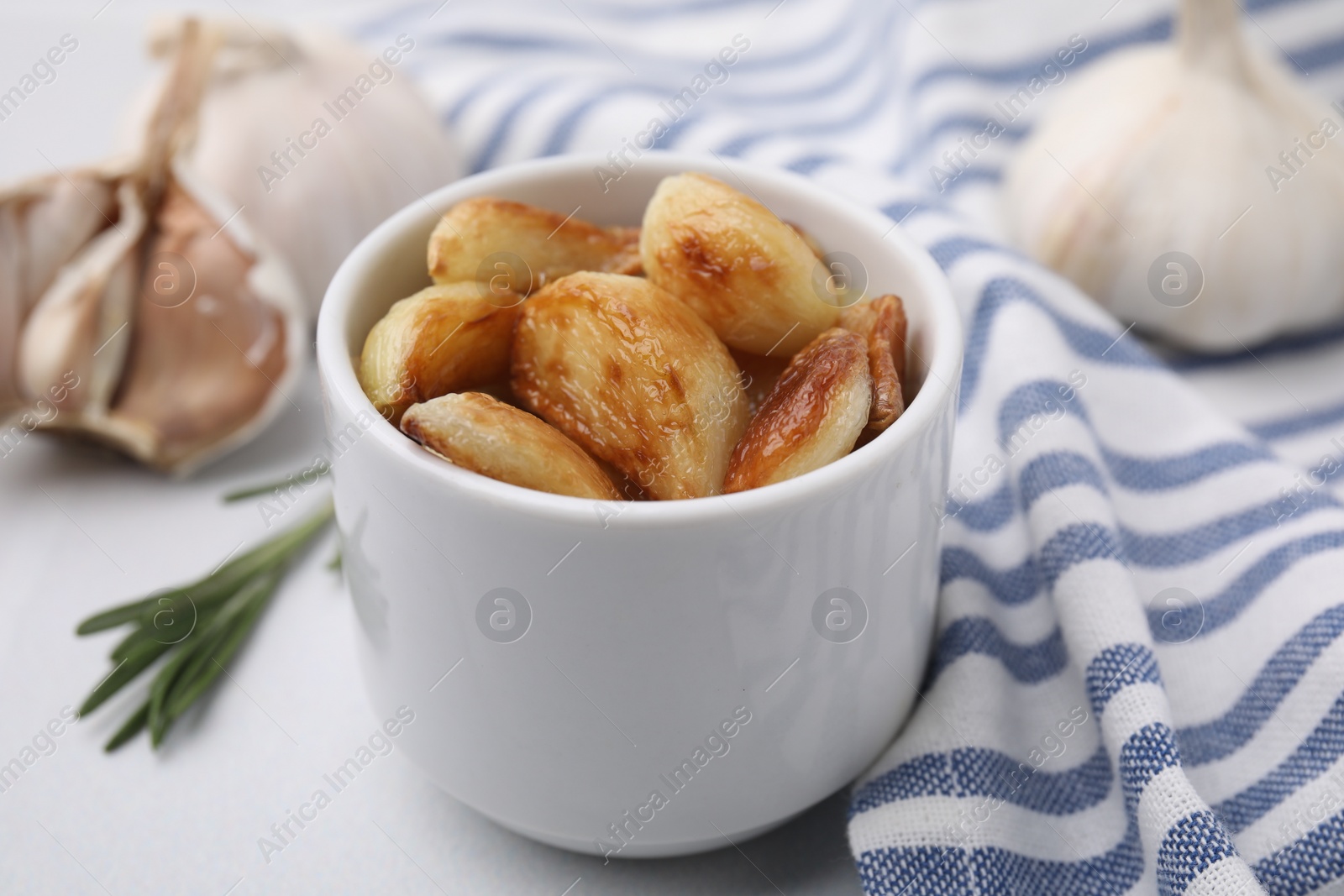 Photo of Fried garlic cloves in bowl on table, closeup