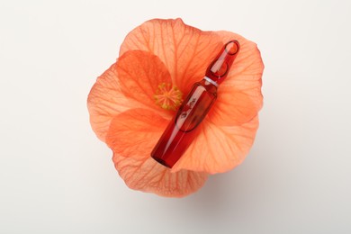 Skincare ampoules and hibiscus flower on white background, top view