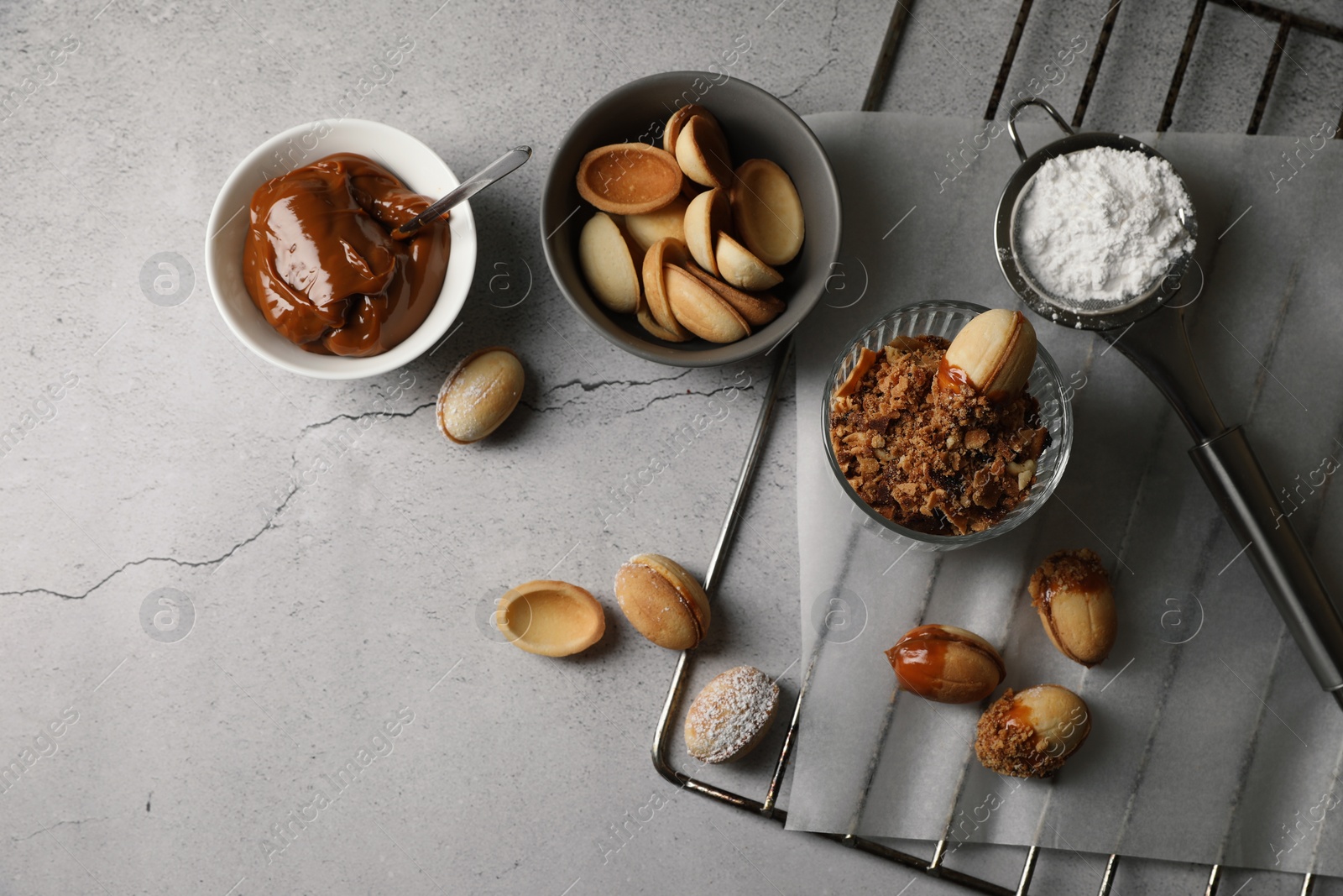 Photo of Delicious walnut shaped cookies with condensed milk on grey table, flat lay