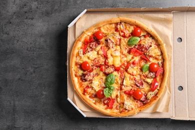 Photo of Cardboard box with delicious pizza on table