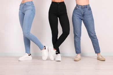 Photo of Women in stylish jeans near white wall, closeup
