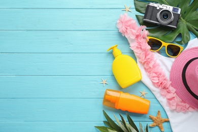 Flat lay composition with beach accessories on light blue wooden background, space for text