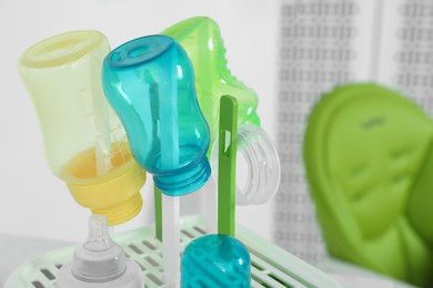 Dryer with baby bottles and nipples after sterilization on white table indoors, closeup