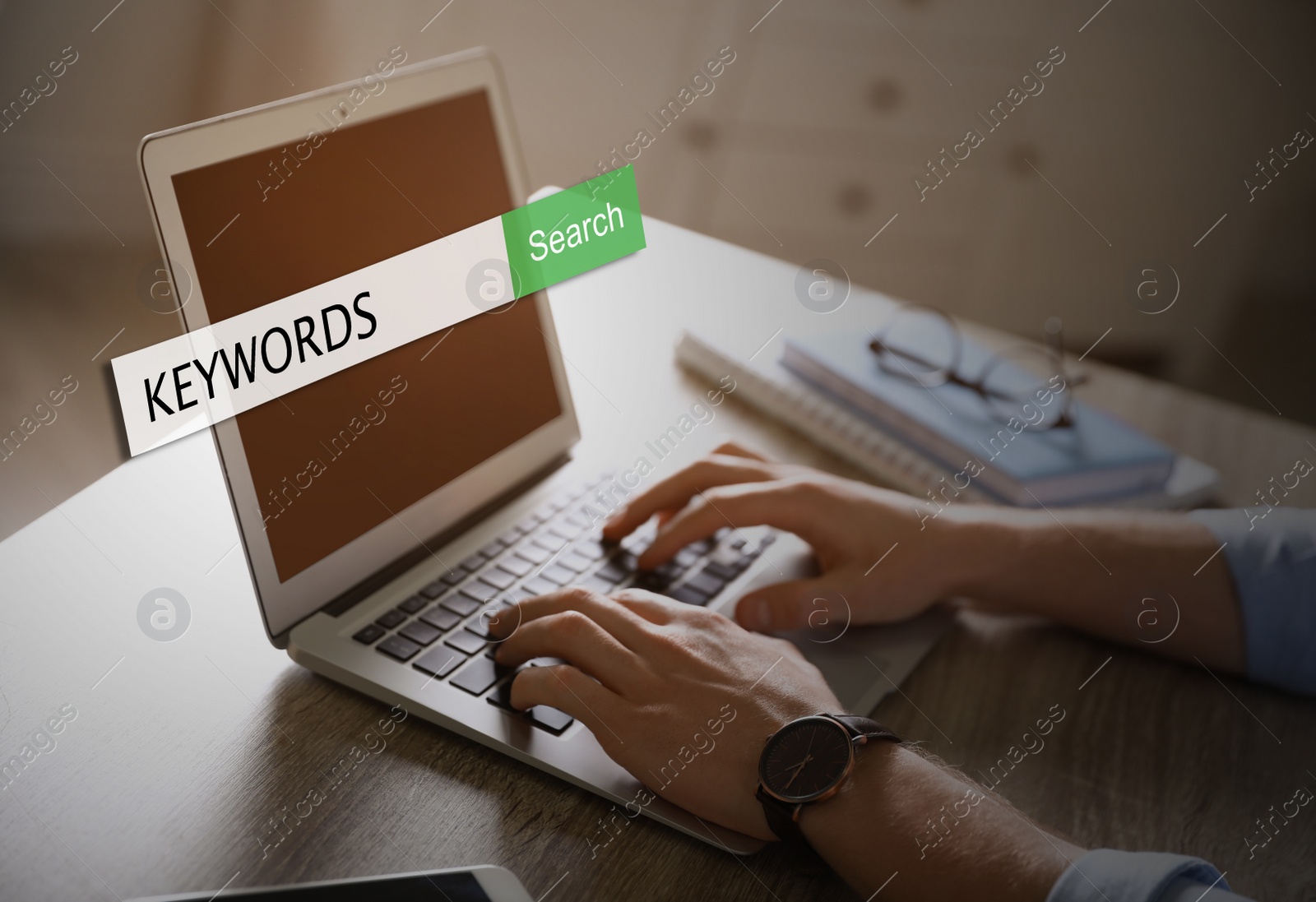 Image of Man with laptop searching for keywords at table, closeup