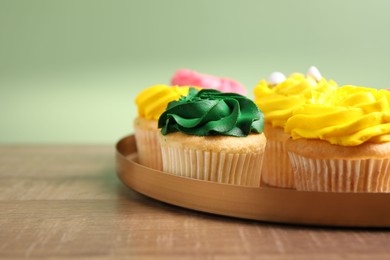 Photo of Delicious cupcakes with bright cream on wooden table, closeup. Space for text