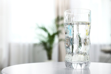 Photo of Glass of water on table in room, space for text. Refreshing drink