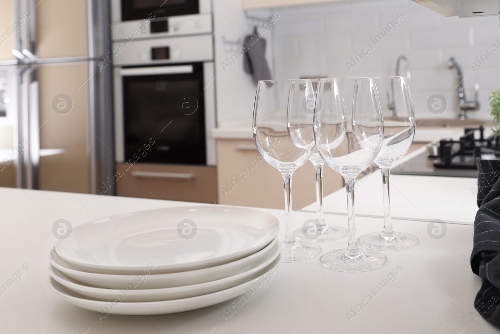 Photo of Stack of clean dishes and glasses on table in kitchen